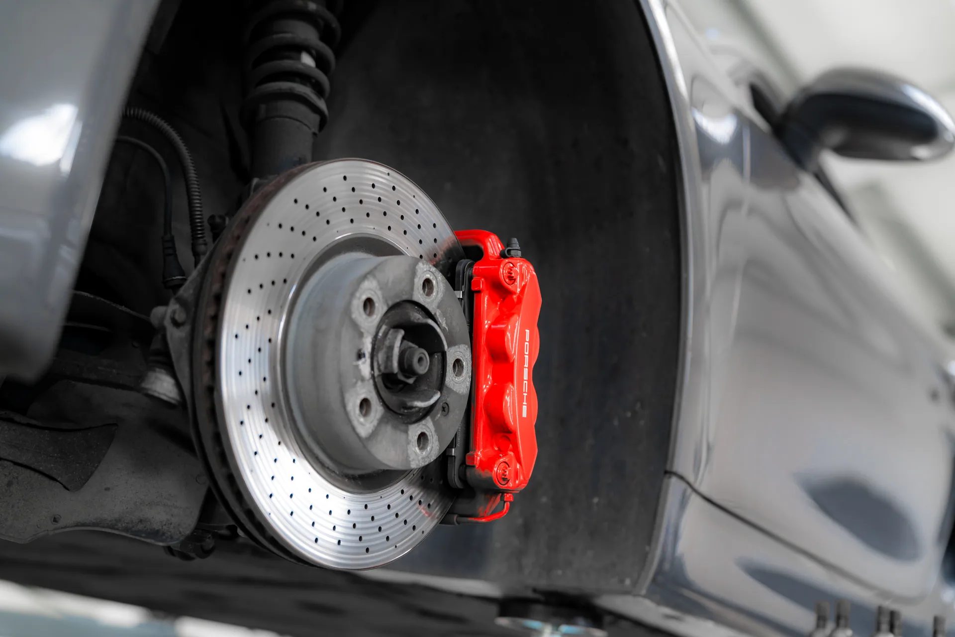 Układ hamulcowy Porsche z widoczną tarczą i czerwonym zaciskiem